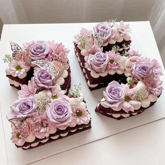 Rode lettertaarten versierd met roze bloemen, witte slagroom en gouden vlinders.