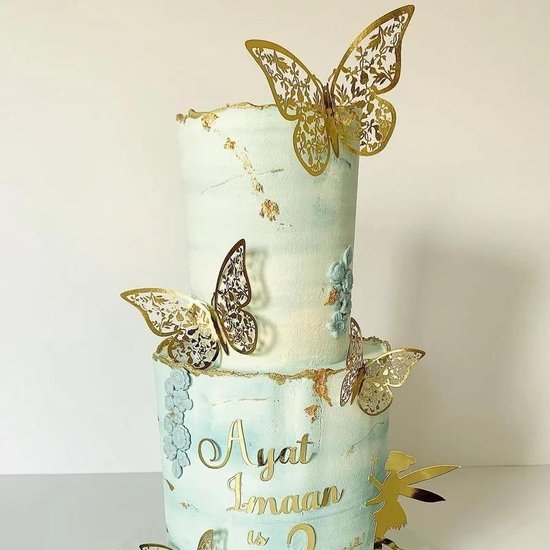 Tweedelige lichtblauwe taart met gouden details, vlindertoppers en bloemen. Tekst 'Ayat Imaan'.