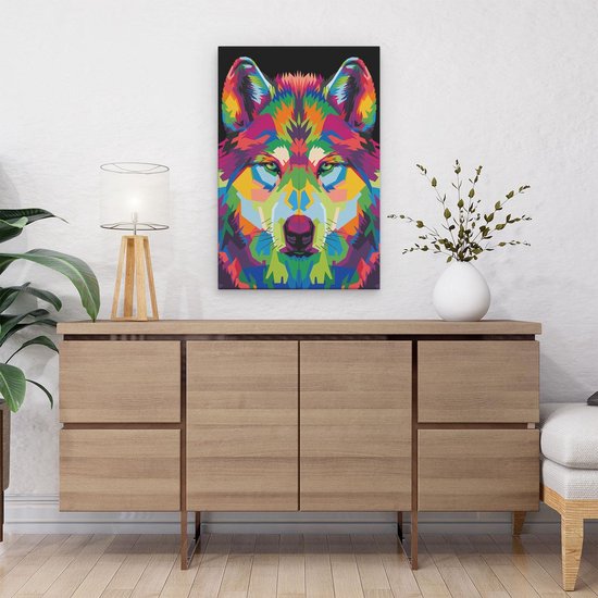 Abstracte wolvenkop in veelkleurige geometrische stijl, hangend aan een witte muur boven een houten dressoir met planten.
