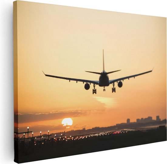 Toile d'un avion atterrissant au coucher du soleil, avec des lumières de ville sur la piste.
