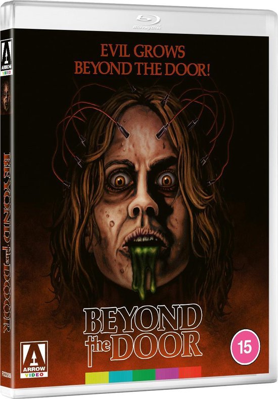 Blu-ray hoes van 'Beyond the Door' met een griezelige vrouw op de voorkant, met draden verbonden aan haar hoofd en groene vloeistof uit haar mond.