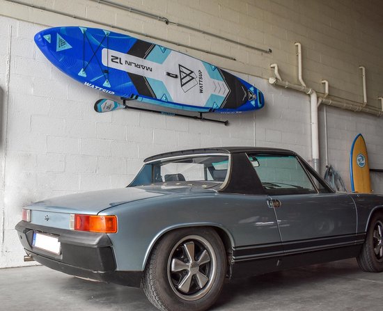 Planche de paddle et pagaie bleues et blanches "Marlin 12" au mur, à côté d'une voiture.