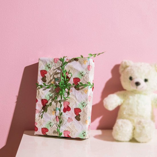 Ingeslagen cadeau met groene klimop en strik, naast een witte teddybeer