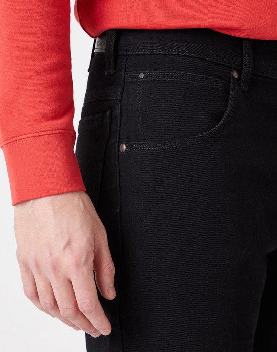 Detail van de voorzakken van een zwarte jeans.