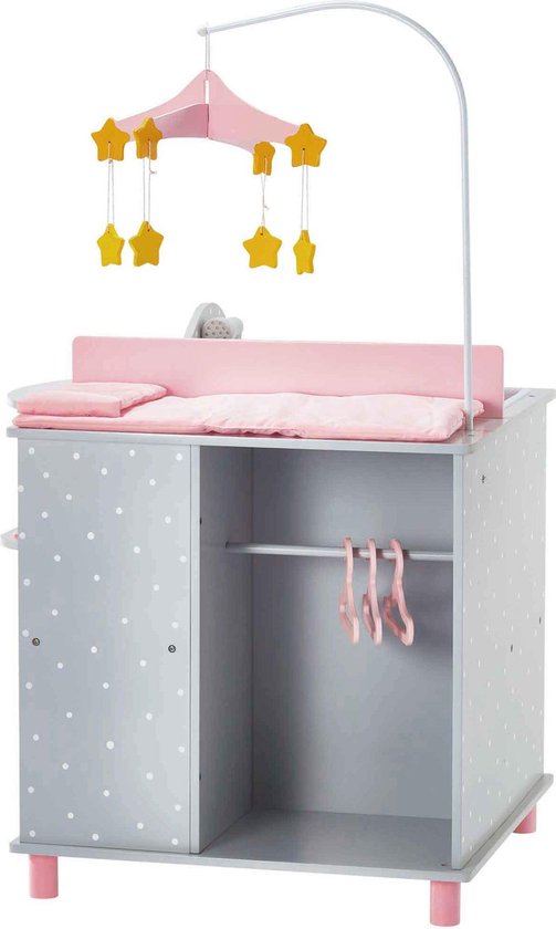 Grijze commode met witte stippen, roze matras en een mobiel met gele sterren. Deurtje open met roze hangers.