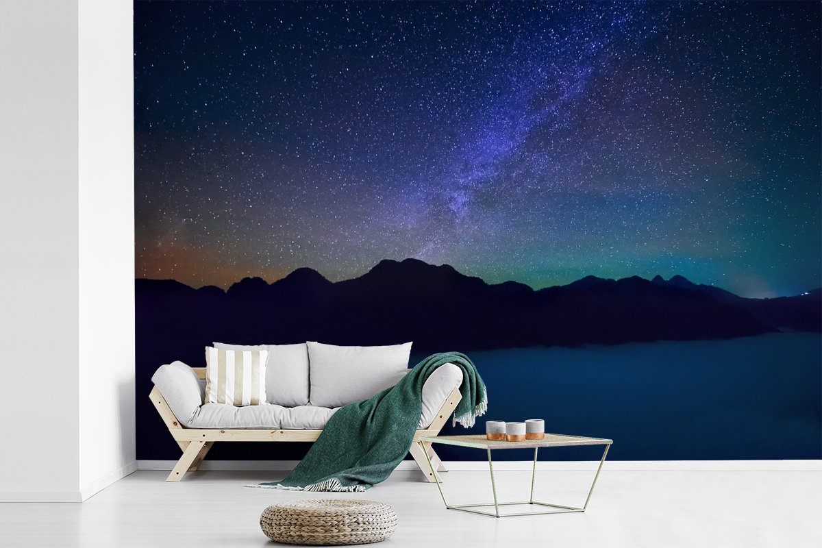 Behang - Fotobehang Een sterrenhemel boven het silhouet van een berg in de nacht - Breedte 600 cm x hoogte 400 cm