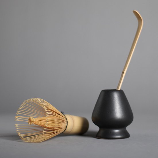 Omgevallen matcha garde van bamboe, met zwarte houder en lepel.