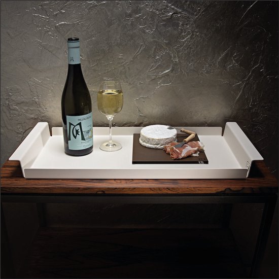 Wit dienblad met fles wijn, glas, kaas en ham, geplaatst op een houten tafel.