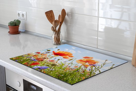 Een inductiebeschermer met een bloemenprint, geplaatst op een wit aanrecht met een kookplaat.