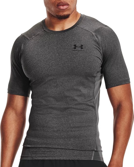 Close-up van een man in een kortarmig grijs sportshirt met donkere naden en logo.