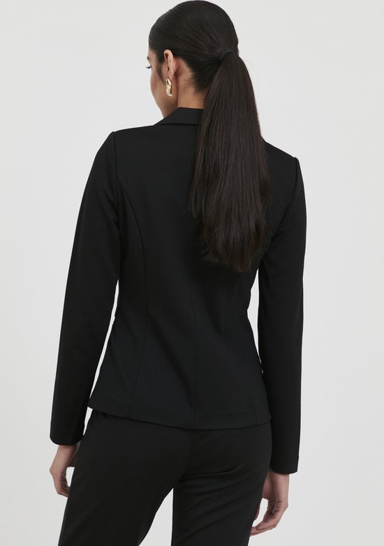 Vrouw met paardenstaart, draagt zwarte blazer en broek, zicht op de achterkant.