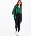 Model draagt een groene vest over een zwart-groen hartjesblouse en een zwarte broek.