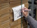 Hand schrijft met Edding 3000 permanent marker op een label tussen dozen.