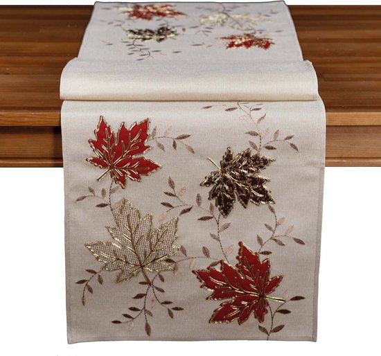 Chemin de table écru orné de feuilles d'automne rouges, brunes et dorées et de brindilles.