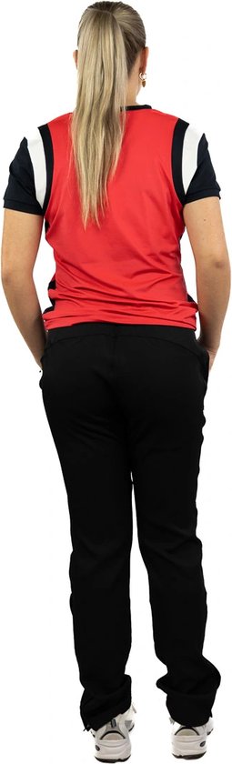 Model draagt een rode sporttop met donkerblauwe mouwen, zwarte trainingsbroek en witte sportschoenen.