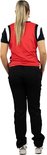 Model draagt een rode sporttop met donkerblauwe mouwen, zwarte trainingsbroek en witte sportschoenen.
