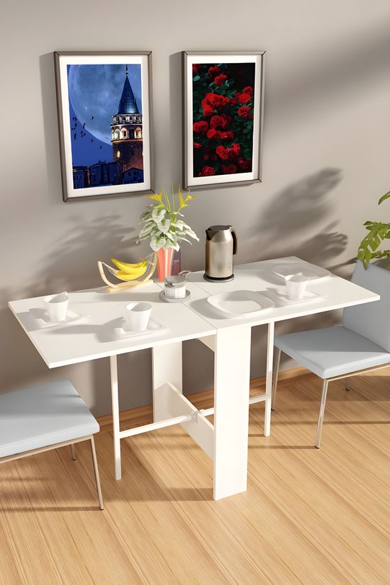 Wit opklapbare eettafel met twee stoelen, twee mokken en een waterkoker op een houten vloer.