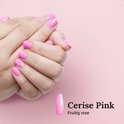Vrouwenhanden met roze 'Cerise Pink' BIAB nagellak, met een staaltje nagellak ernaast.