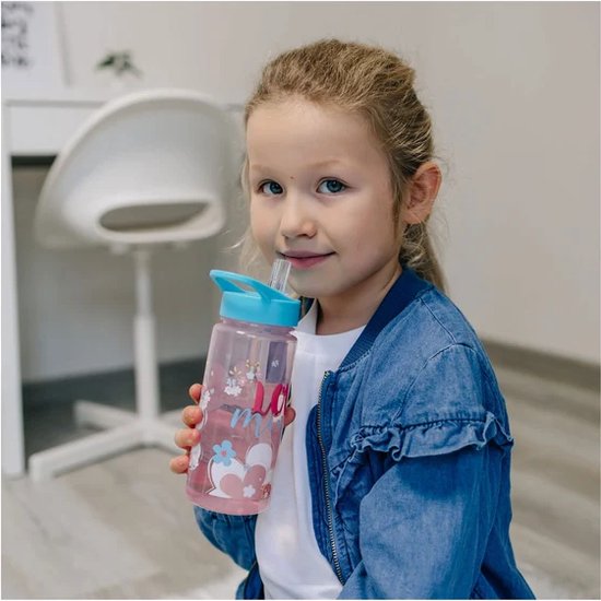 Une fille aux cheveux blonds boit dans une bouteille rose Minnie Mouse avec un bouchon bleu et une paille.