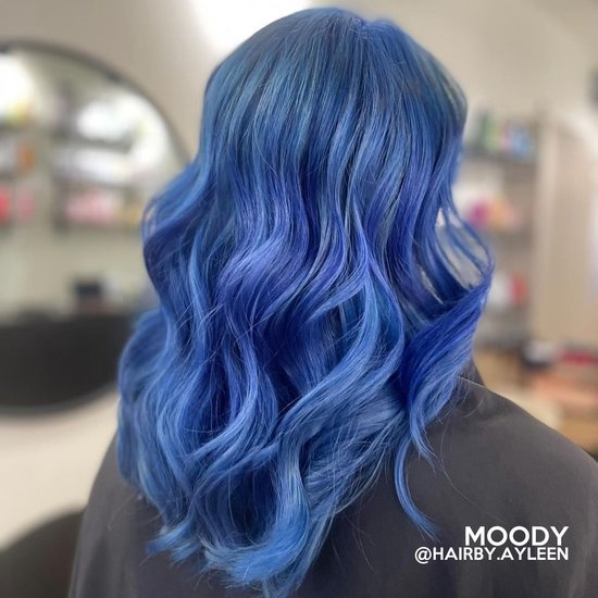 Model met golvend, middellang haar in een levendige blauwe kleur.