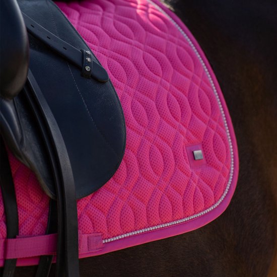 Schoppend roze dressuur zadeldek met een grijze rand en diamantjes.