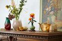 Chrysanthème LEGO dans un pot vert pastel sur socle en bois, sur meuble en bois avec vases.