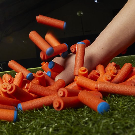 Hand pakt oranje Nerf darts uit een hoop.