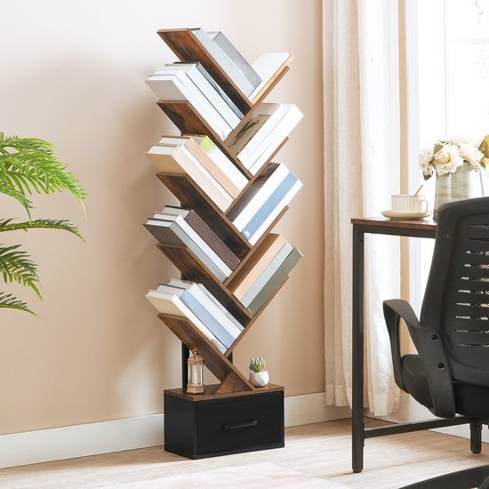 Een boekenkast in boomvorm staat in een woonkamer, gevuld met boeken, naast een raam met gordijnen en een plant.