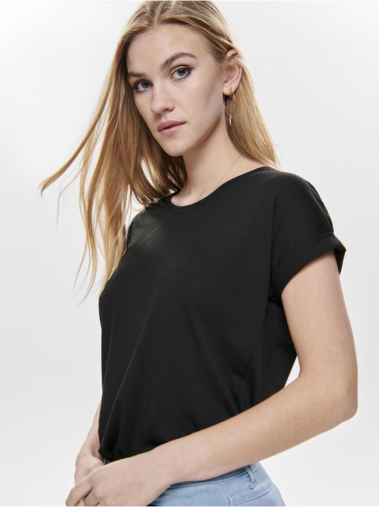 Model in zwart T-shirt met opgerolde mouwen en lichte jeans.