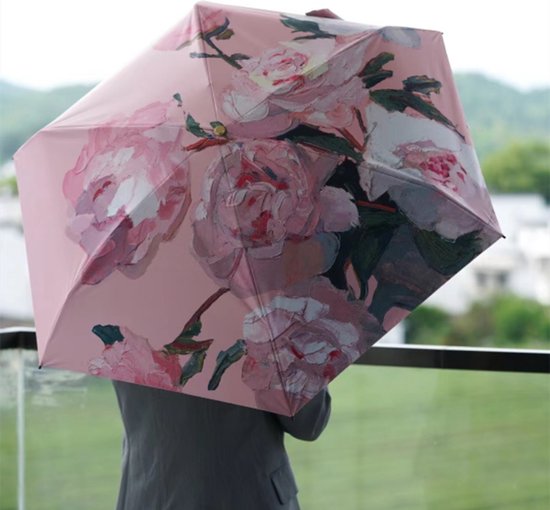 Persoon in grijs jasje, van achteren gezien, die een geopende paraplu met een roze pioenrozen schilderij vasthoudt.