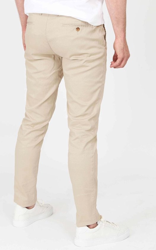 Achterkant van een mannen chino in lichtbeige, gedragen met witte sneakers.