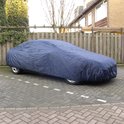 Donkerblauwe autohoes op een oprit, beschermt een sedan.