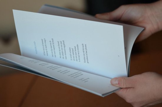 Open boek met Nederlandse gedichten. Handen houden het boek vast. Pagina's met tekst.