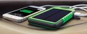 Groene zonnepaneel powerbank en iPhone in auto met opgeladen batterij-icoon.