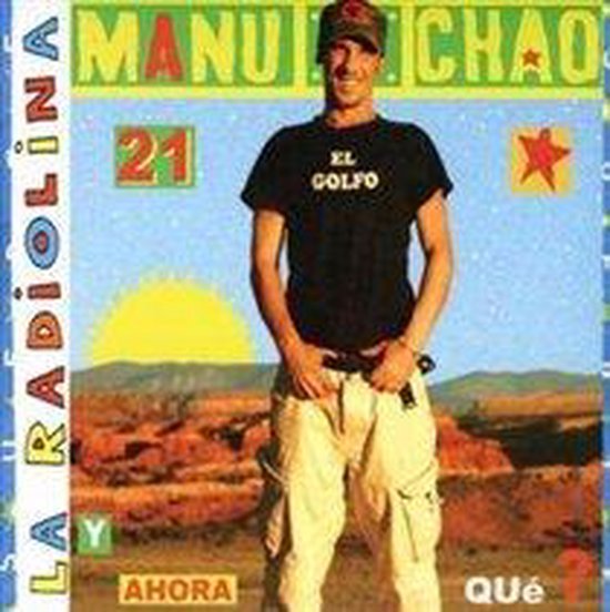 Manu Chao, mains dans les poches, porte un T-shirt noir "EL GOLFO" et un pantalon cargo beige.
