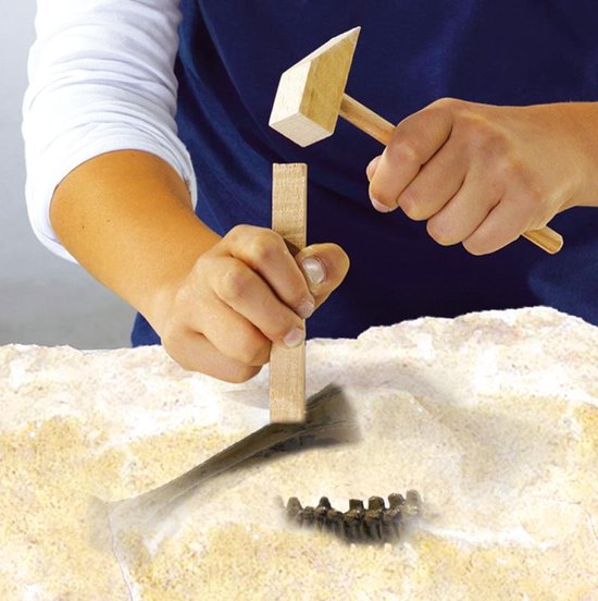 Kinderhanden gebruiken een hamer en beitel om een dinosaurusbot uit steen te graven.