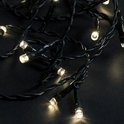 Detailopname van donkergroene kerstverlichting met warm witte LEDlampjes.