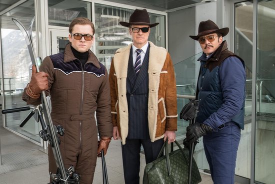 Drie mannen in skikleding, met skipassen en een tas.