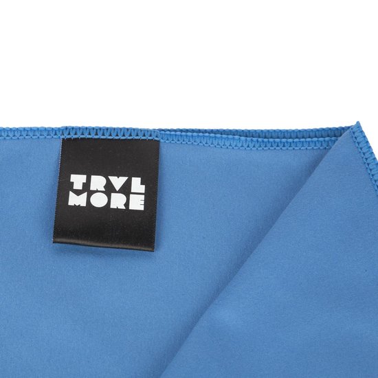 Blauwe microvezelhanddoek met een zwart label met de tekst "TRVL MORE" in witte letters.