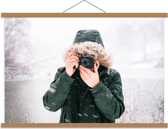 Schoolplaat – Man in de Sneeuw met een Donkere Jas met een Bontkraag en een Camera - 90x60cm Foto op Textielposter (Wanddecoratie op Schoolplaat)