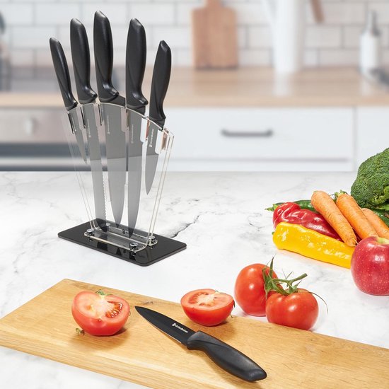 Zwart messenblok, snijplank met tomaten en een mes, groenten op tafel