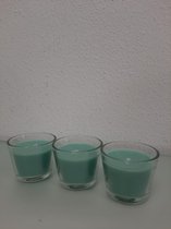 Drie aquablauwe kaarsen in een glazen potje