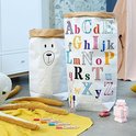 Twee grote papieren zakken in een kinderkamer, één met een beertje, de ander met het alfabet.