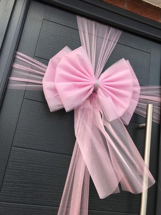 Grote roze tule strik met strass-centrum bevestigd aan een donkergrijze voordeur.