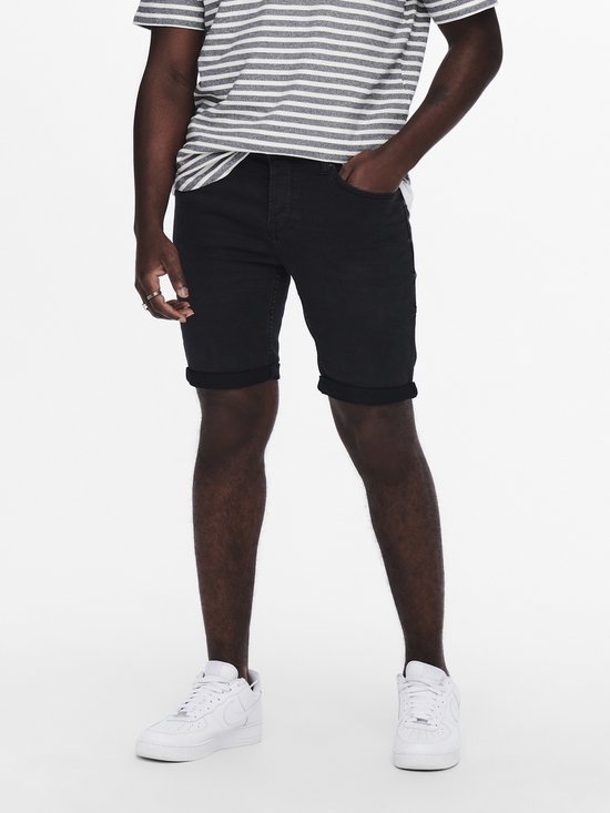 Man met gestreept t-shirt en zwarte denim shorts, witte sneakers.