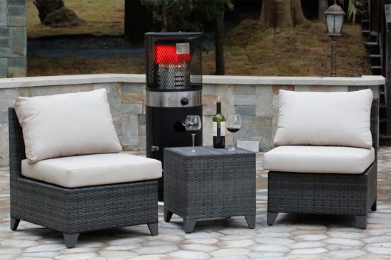 Zwarte staande terrasverwarmer met zilverkleurige details, tussen rotan lounge stoelen en een bijzettafel met wijn.