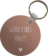 Sleutelhanger - Engelse quote Good vibes only! met een hartje tegen een bruine achtergrond - Plastic - Rond - Uitdeelcadeautjes