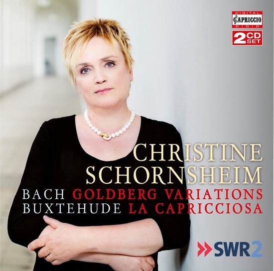 Christine Schornsheim draagt een parelketting, haar opgestoken, staand tegen een muur. Twee CD's.