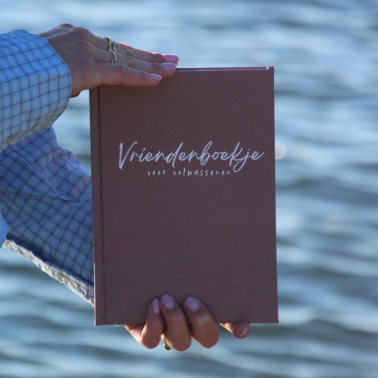 Een roze invulboekje met de tekst 'Vriendenboekje voor volwassenen' in witte sierlijke letters.