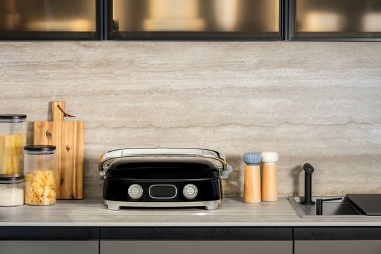 Zwarte contactgrill met chromen handgreep, gesloten, op een aanrecht.